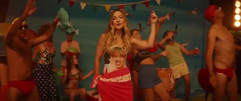 Holiday: a crowd in swimwear dances and throws streamers on a painted beach set