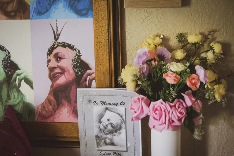 Maggie May: a memorial card, roses and a painted portrait on a side table