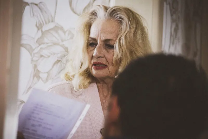 Maggie May: an older blonde woman reads from a sheet of paper